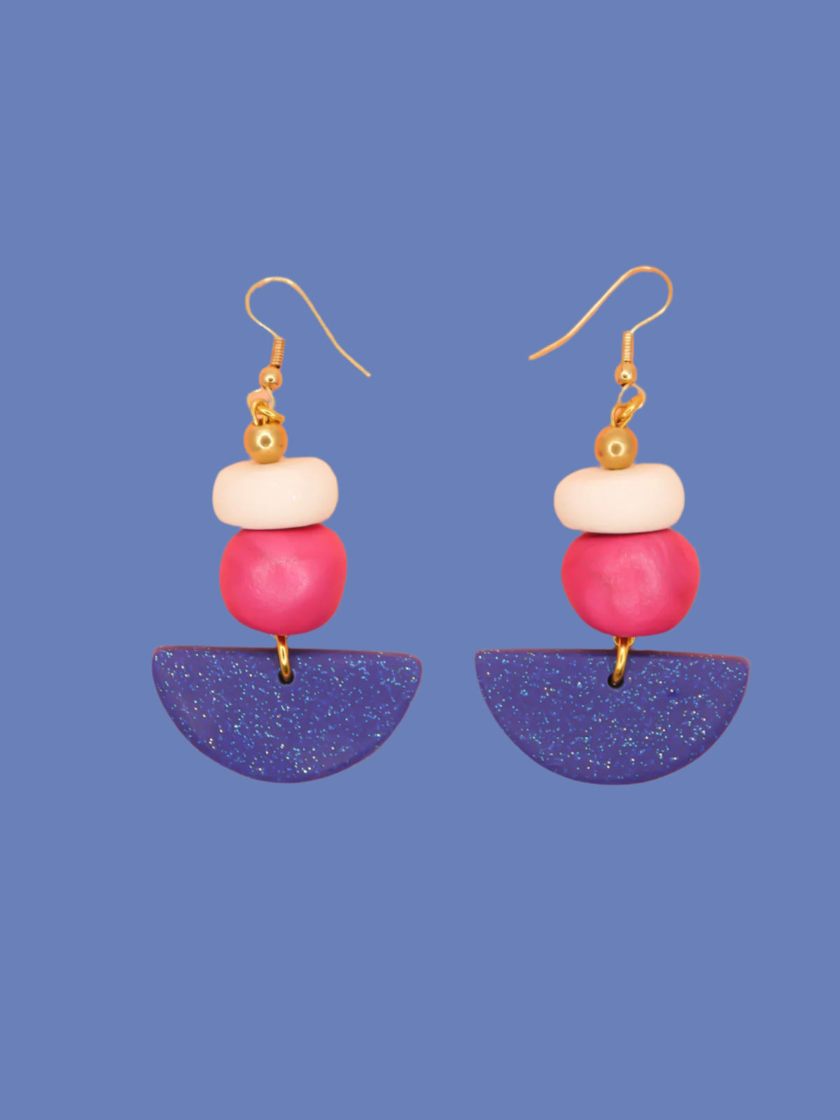 Geometric dangle statement earrings with a blue glitter semi circle, hand rolled beads in pink metallic and white glitter with a brass ball bead hung from gold plated ear wires