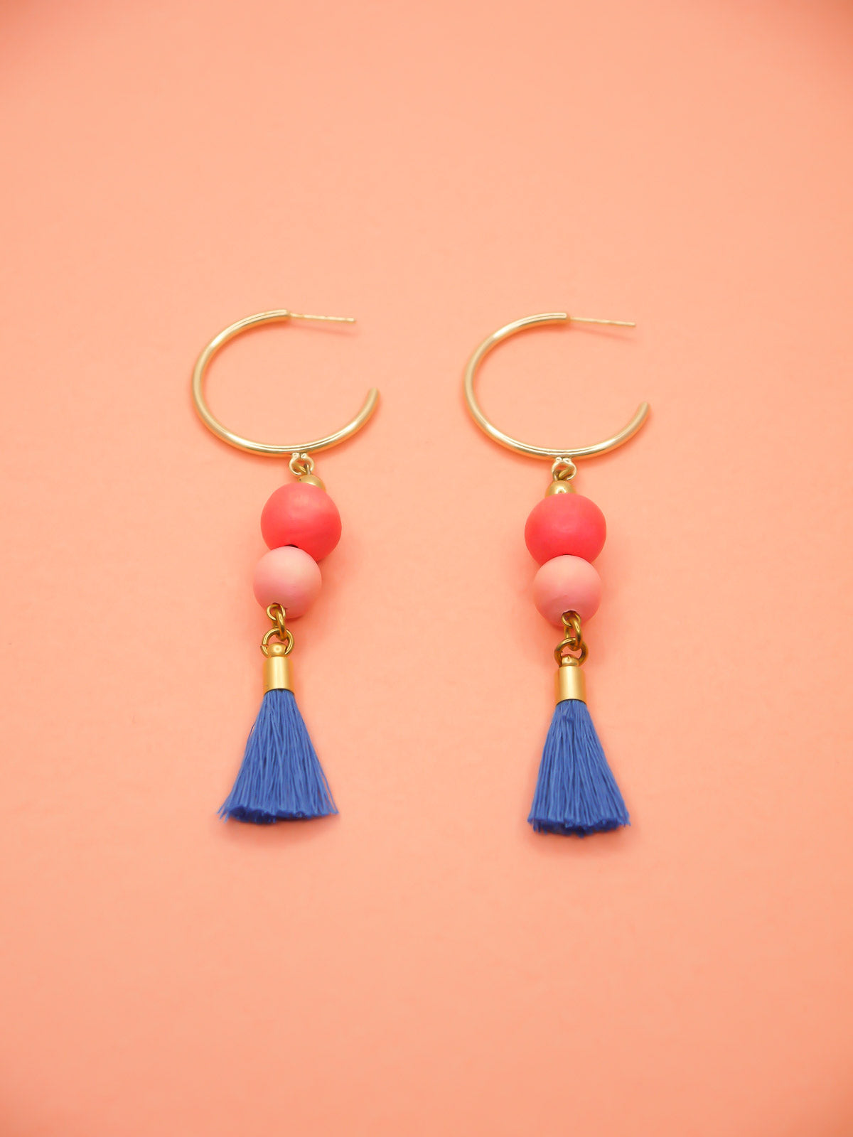 Gold hoop beaded tassel dangle earrings with wooden beads in salmon and pink paired with a sapphire blue tassel and gold hoops