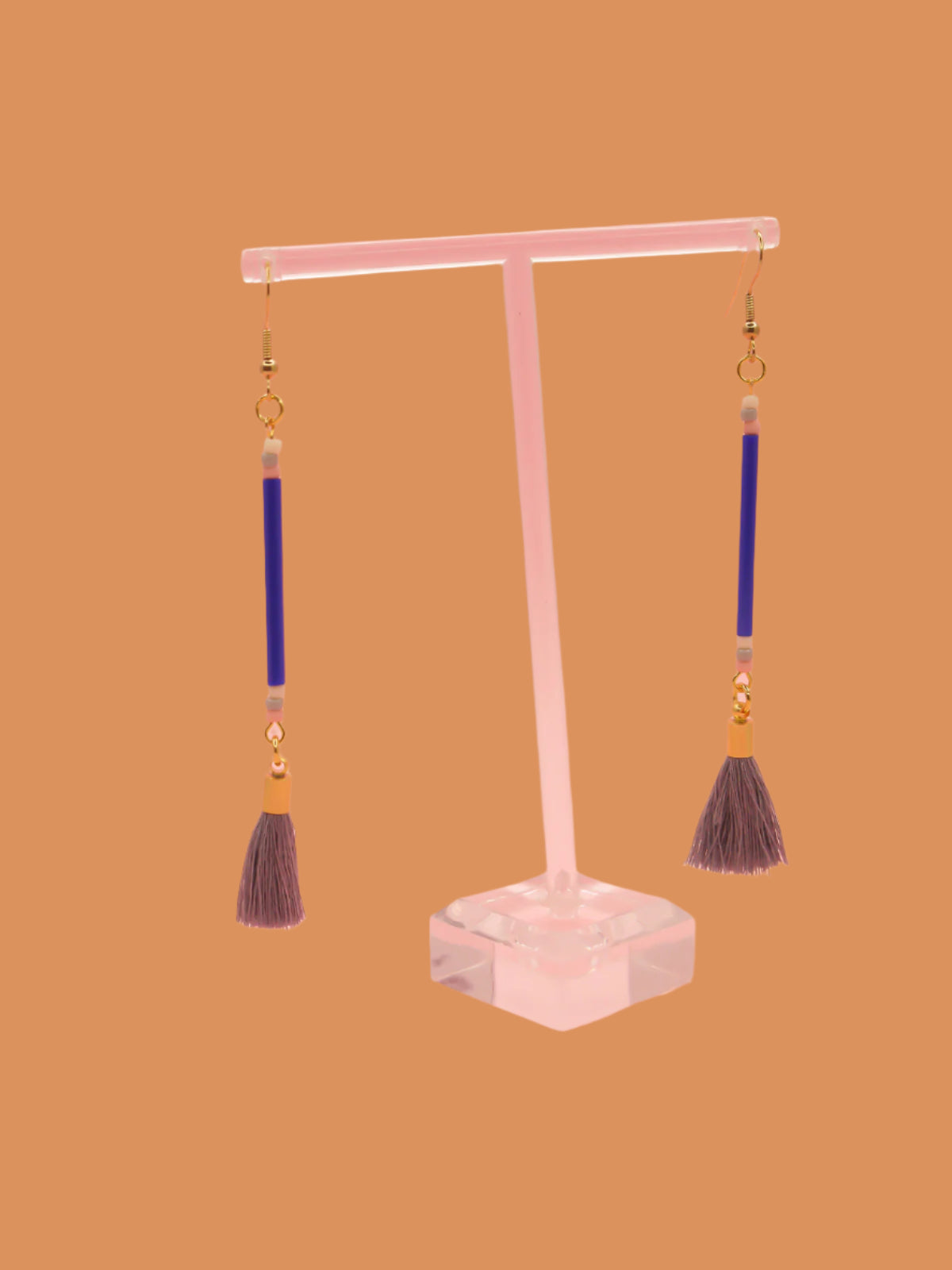 Long delicate bead stick dangle earrings featuring blue tube beads with contrasting seed beads in pink, white & grey, paired with a grey cotton tassel & hung from gold plated nickel free ear wires