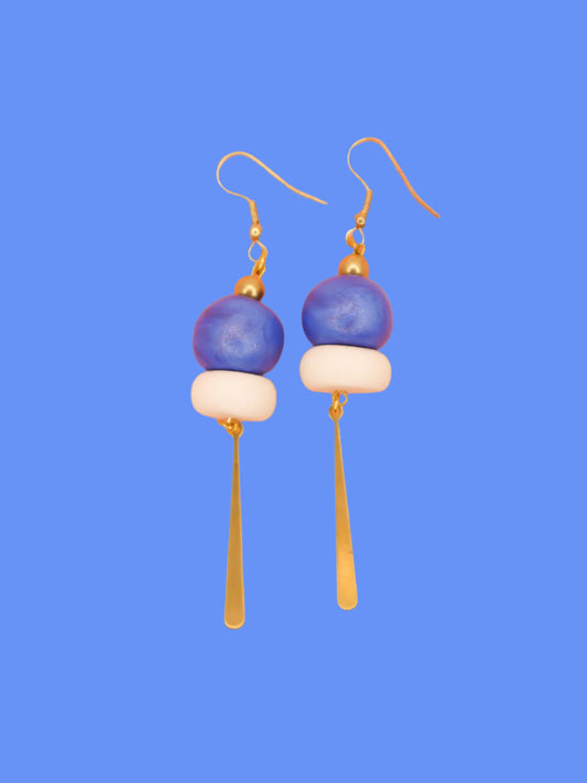 Metallic bead dangle earrings with two hand rolled metallic beads in blue and white glitter with a brass stick charm, hung from gold plated ear wires