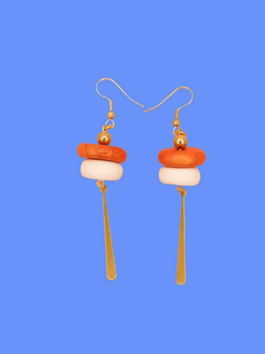 Metallic bead dangle earrings with two hand rolled metallic beads in rust and white glitter with a brass stick charm, hung from gold plated ear wires