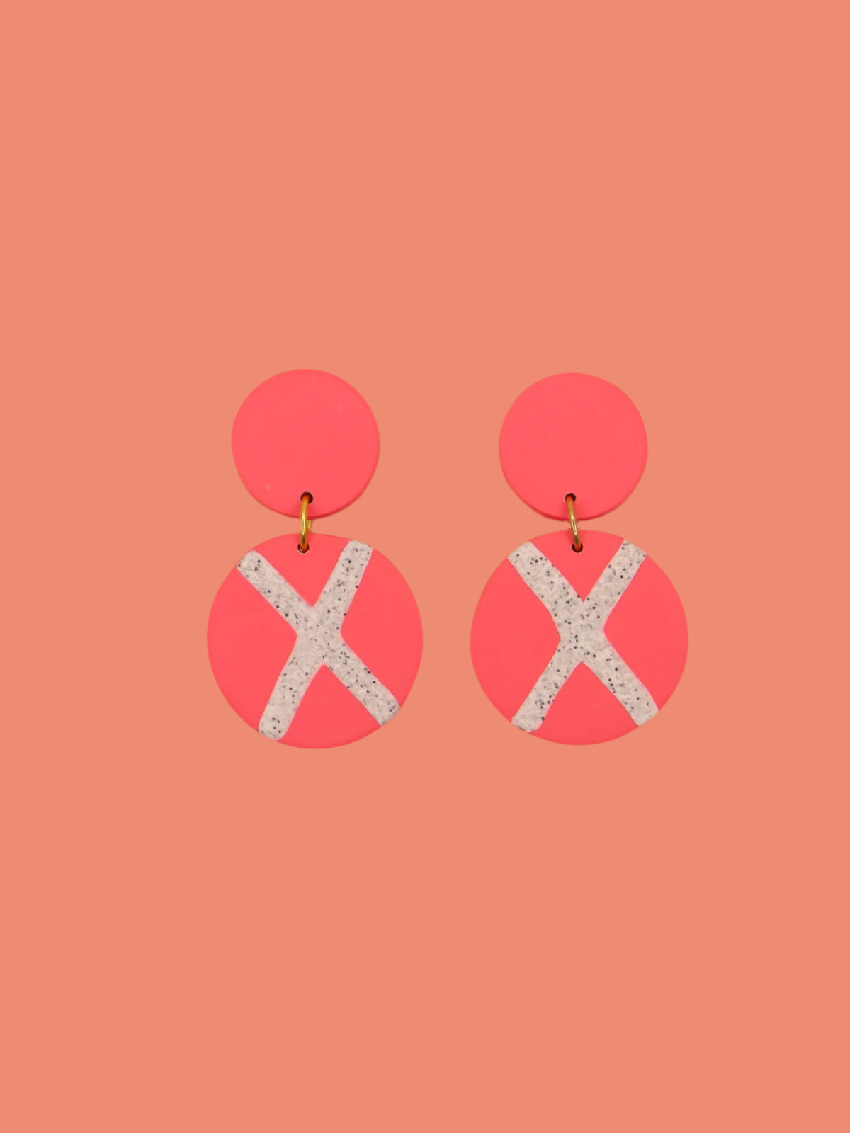 Polymer clay dangle statement earrings with a pink stud connected to a pink circle with a granite cross in the centre