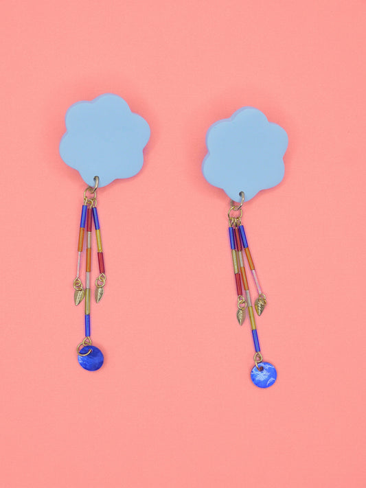 Colourful earrings of blue clouds with glass dangle tube beads on a pink background
