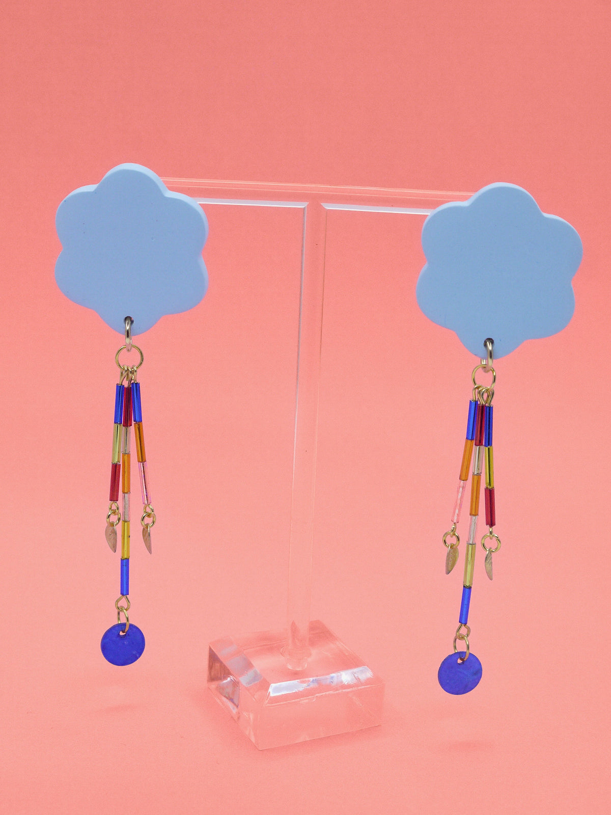 Colourful earrings of blue clouds with glass dangle tube beads on a pink background