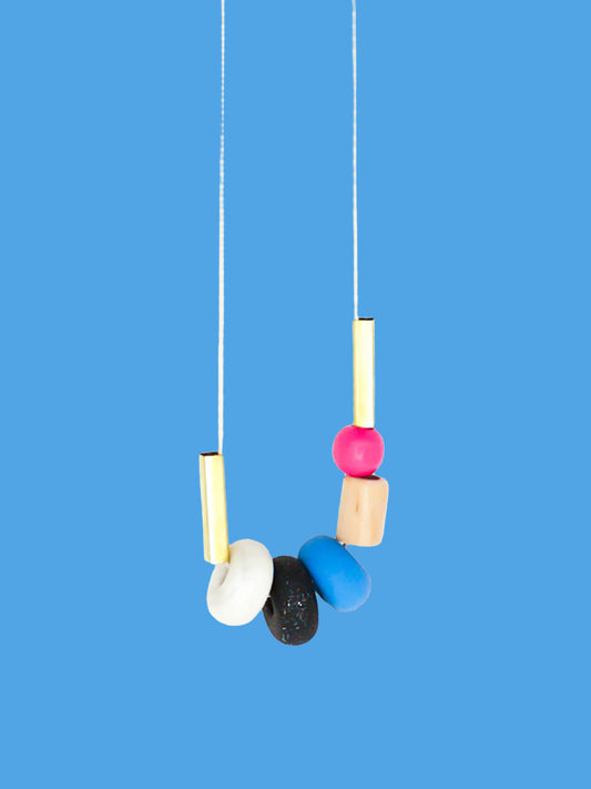 Lightweight geometric colourful bead necklace with 3 handmade polymer clay beads in marble, blue & black glitter- wood tube bead & pink wood bead, brass tube beads on either side, strung on a cotton cord with a blue wood bead knotted at the end