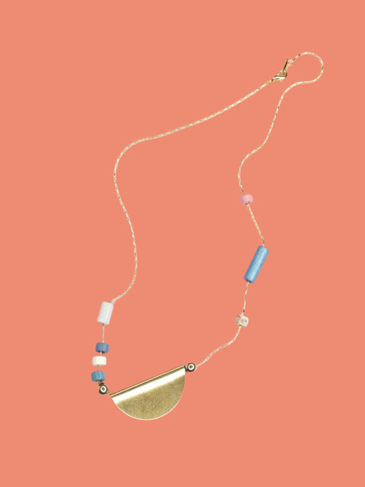 Lightweight & delicate ceramic beaded necklace with a brass semi circle pendant in the centre with ceramic tube beads on either side in pink, blues, white & silver, strung on a thin gold plated snake chain.