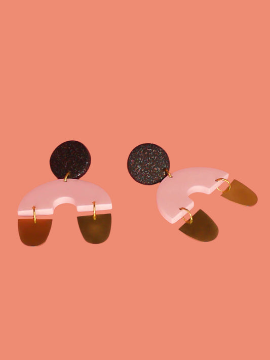 Large geometric arch dangle chandelier earrings with a black glitter stud, connected to a pink semi circle with two brass semi circles hanging off either side of the arch. Made from polymer clay with stainless steel posts.