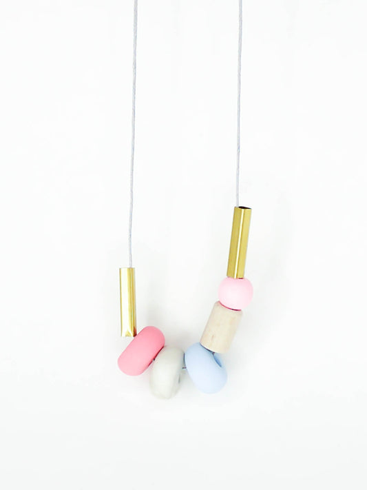 Lightweight geometric colourful bead necklace with 3 handmade polymer clay beads in pink, marble & blue- wood tube bead & pink wood bead, brass tube beads on either side, strung on a cotton cord with a wood bead knotted at the end