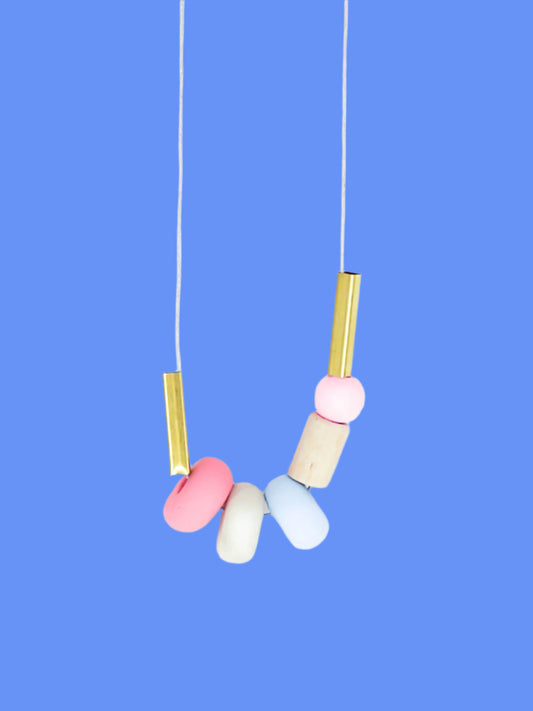Lightweight geometric colourful bead necklace with 3 handmade polymer clay beads in pink, marble & blue- wood tube bead & pink wood bead, brass tube beads on either side, strung on a cotton cord with a wood bead knotted at the end