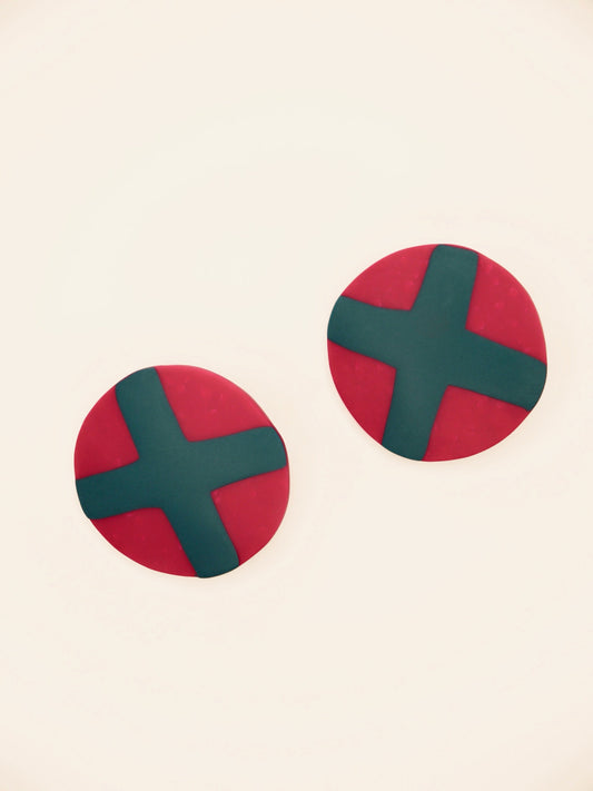Fuchsia studs with green cross geometric earrings on a beige background