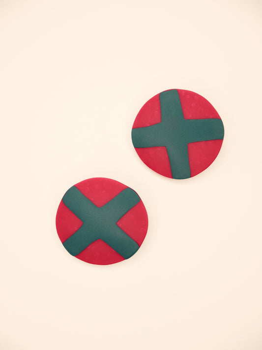 Fuchsia studs with green cross geometric earrings on a beige background
