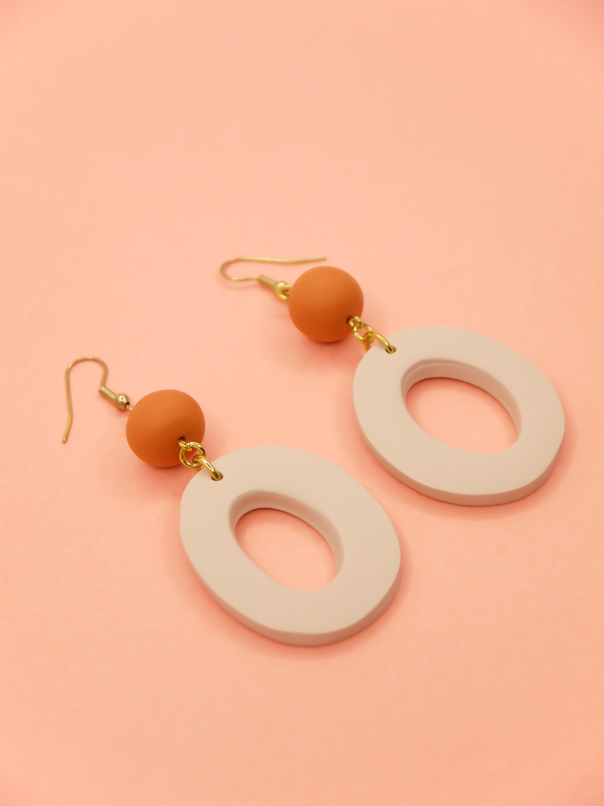 Modern hoop dangle statement earrings with a beige hoop & terracotta bead, hung from brass hooks. Handmade from polymer clay.