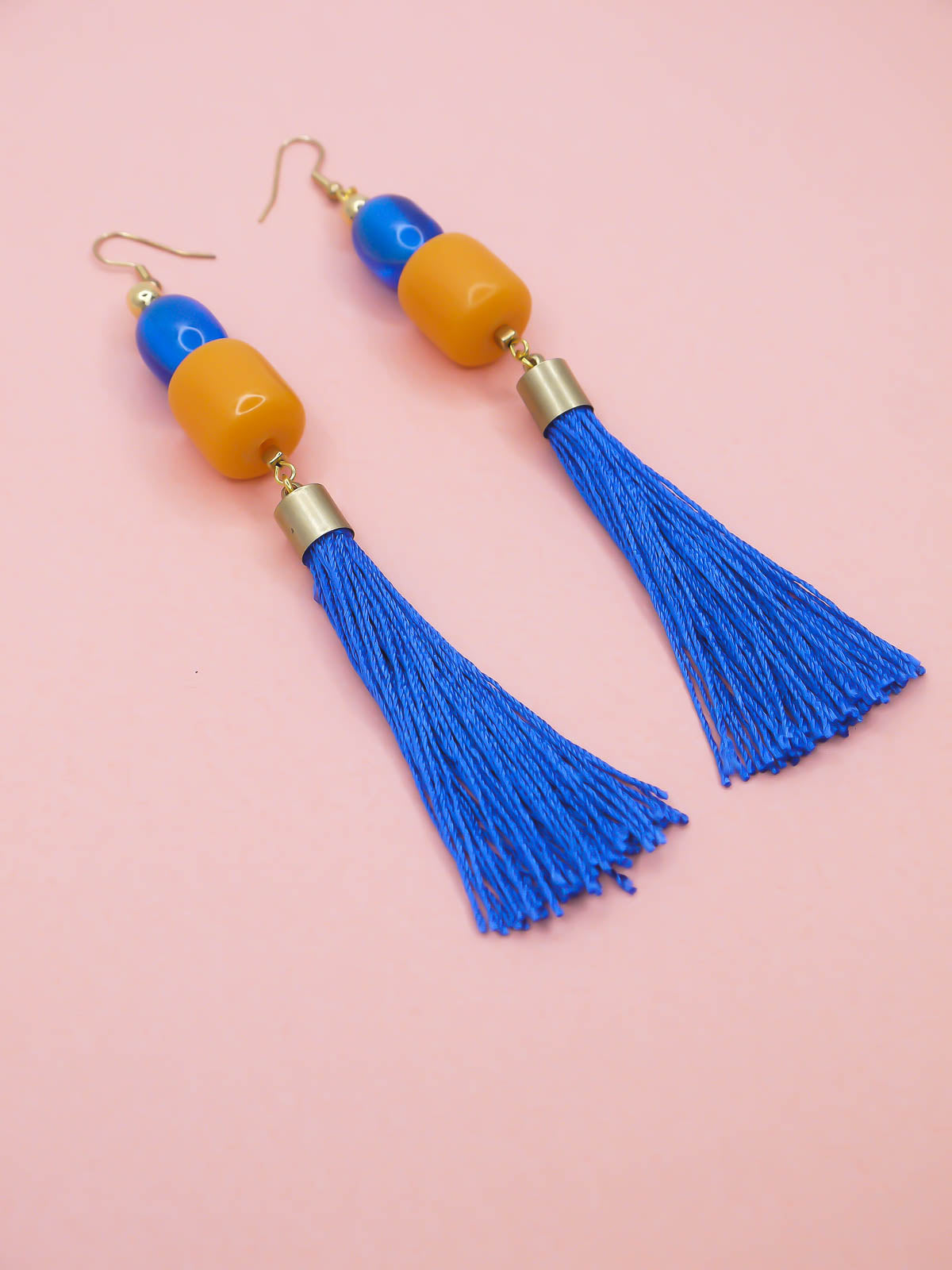 Colorful tassel earrings on a pink background