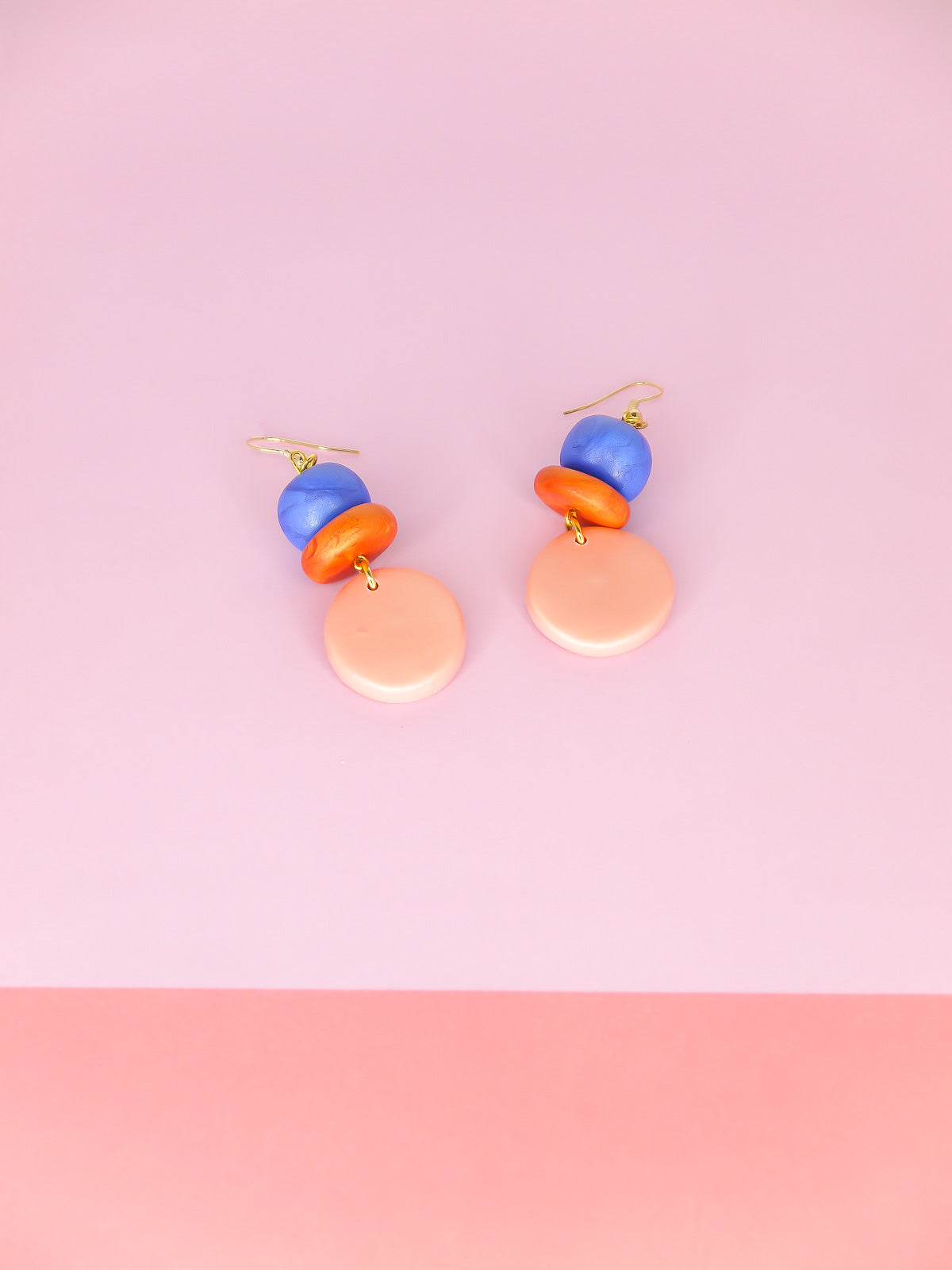 Lightweight metallic beaded dangle earrings with a rose gold circle, topped with hand rolled metallic beads in rust and blue, hung from gold plated ear wires