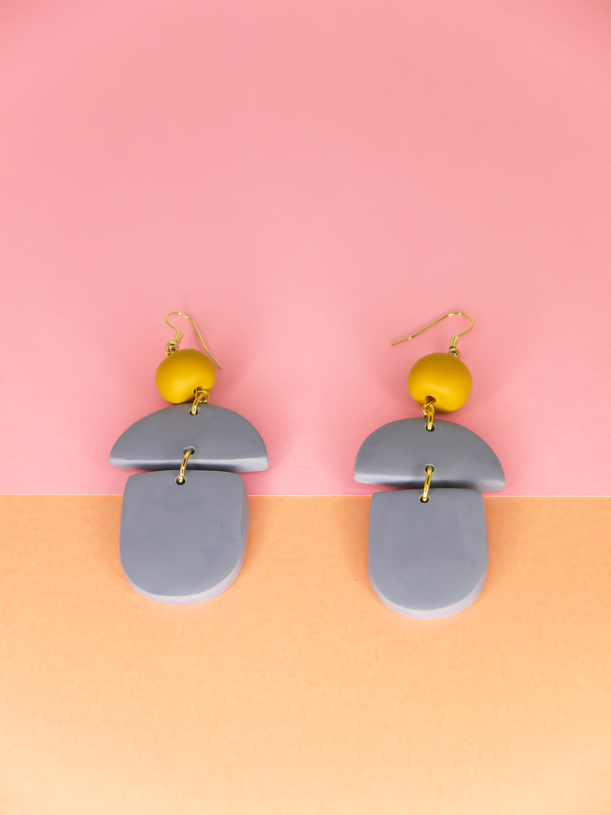 Geometric lightweight dangle statement earrings in bluestone arch and semi circles with a hand rolled mustard bead hung from gold plated nickel free ear wires