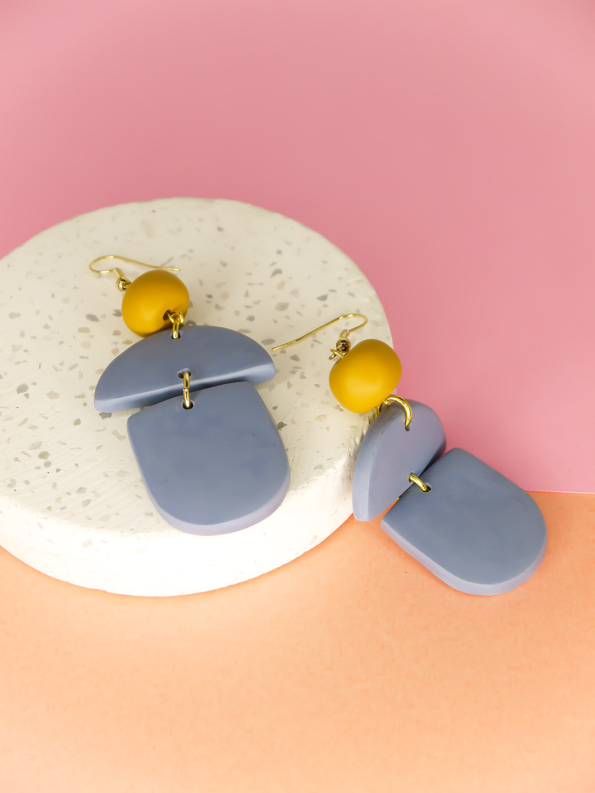 Geometric lightweight dangle statement earrings in bluestone arch and semi circles with a hand rolled mustard bead hung from gold plated nickel free ear wires