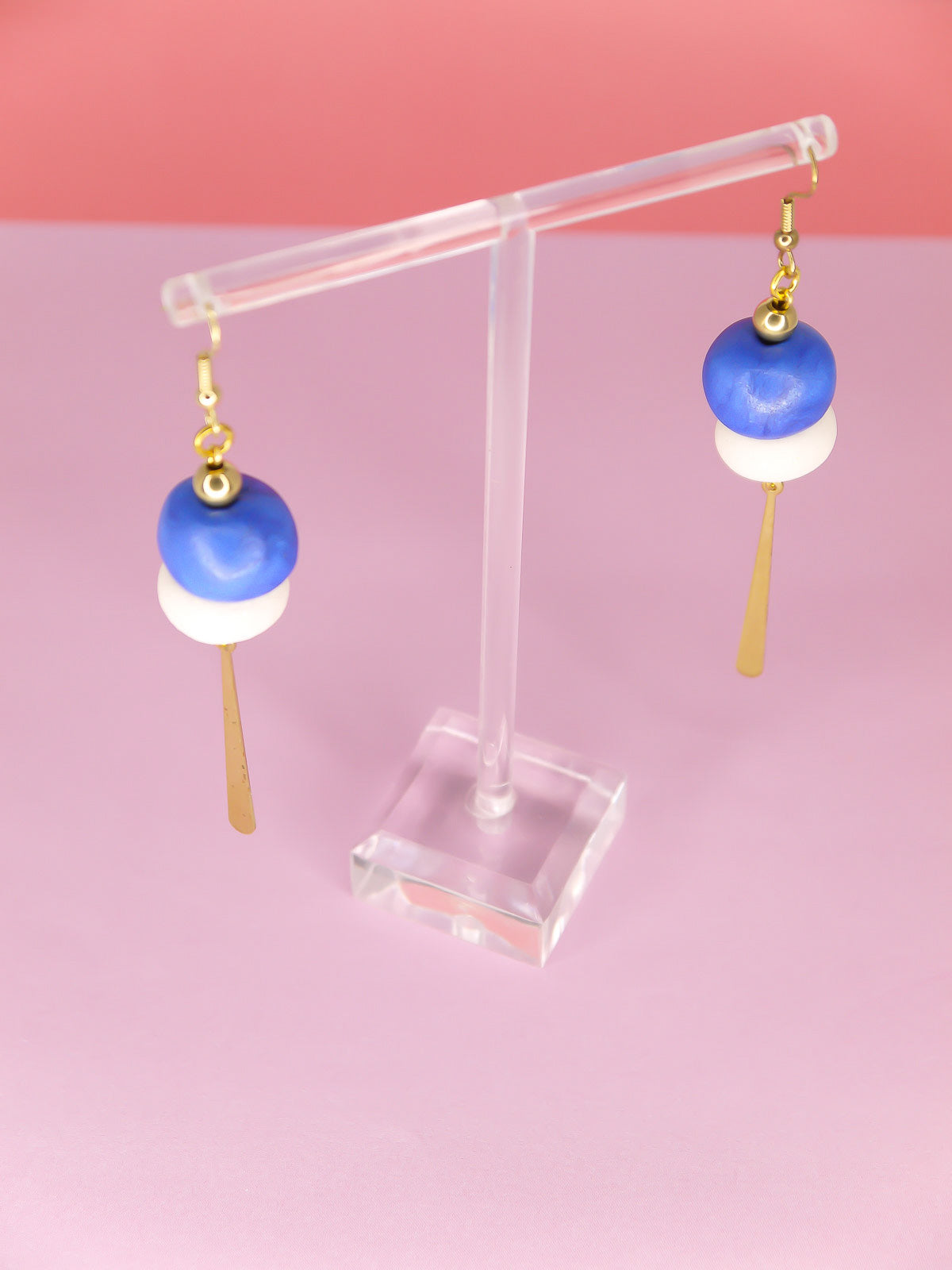 Metallic bead dangle earrings with two hand rolled metallic beads in blue and white glitter with a brass stick charm, hung from gold plated ear wires