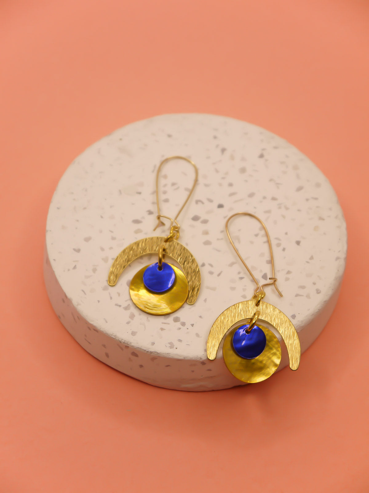 Lightweight geometric dangle earrings with a textured brass semi circle charm & a yellow shell disk with a blue shell disk overlapped, hung from gold plated kidney ear wires