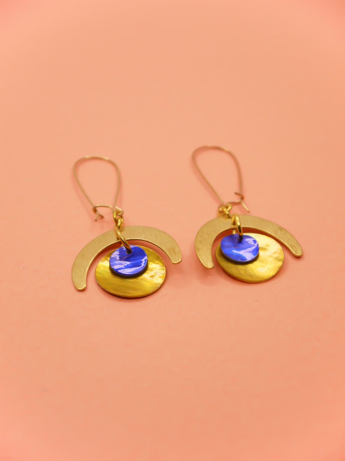 Lightweight geometric dangle earrings with a textured brass semi circle charm & a yellow shell disk with a blue shell disk overlapped, hung from gold plated kidney ear wires