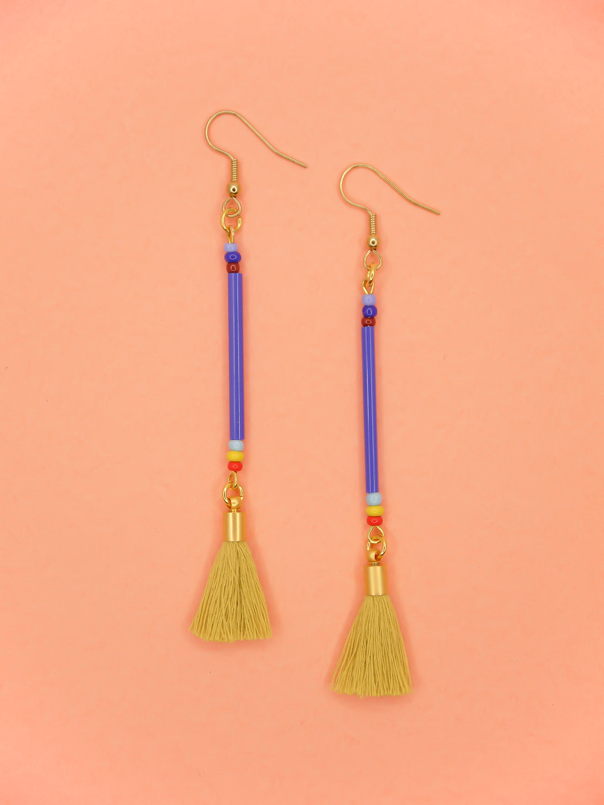 Long bead stick dangle earrings with blue glass tube beads & contrasting seed beads in blue, red & yellow. Paired with a chartreuse cotton tassel and hung from gold plated nickel free ear wires