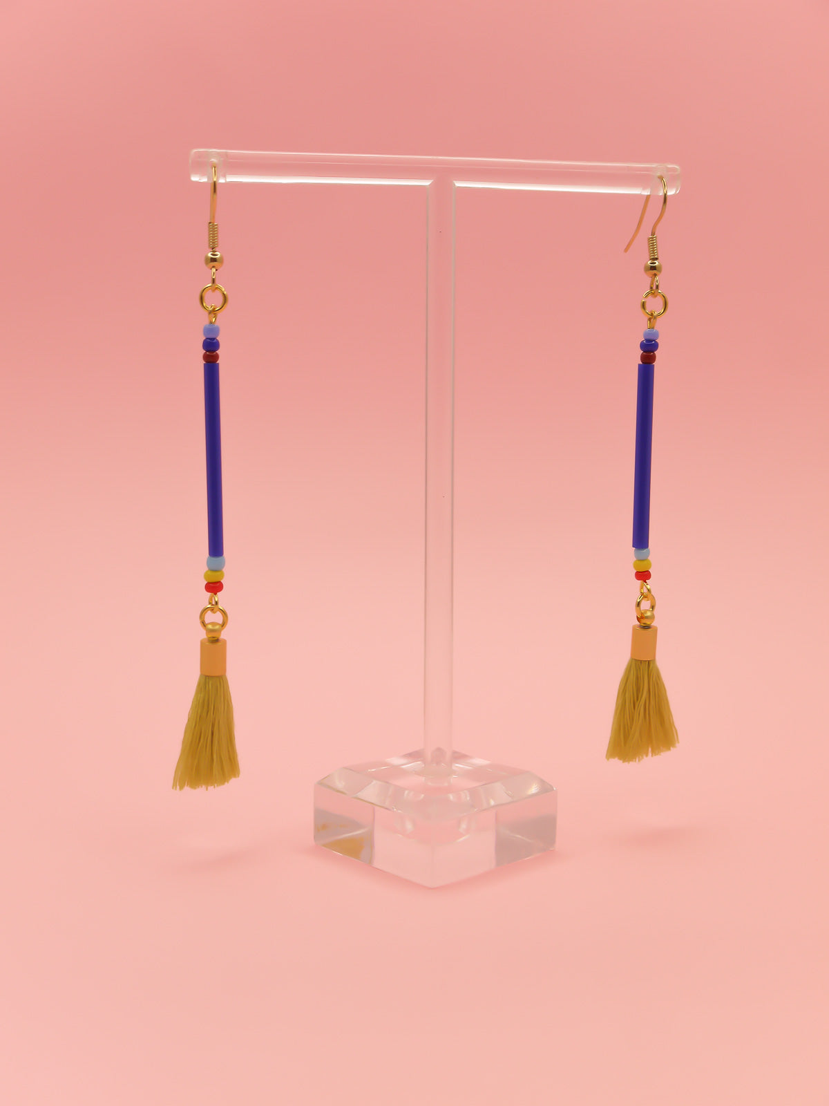 Long bead stick dangle earrings with blue glass tube beads & contrasting seed beads in blue, red & yellow. Paired with a chartreuse cotton tassel and hung from gold plated nickel free ear wires