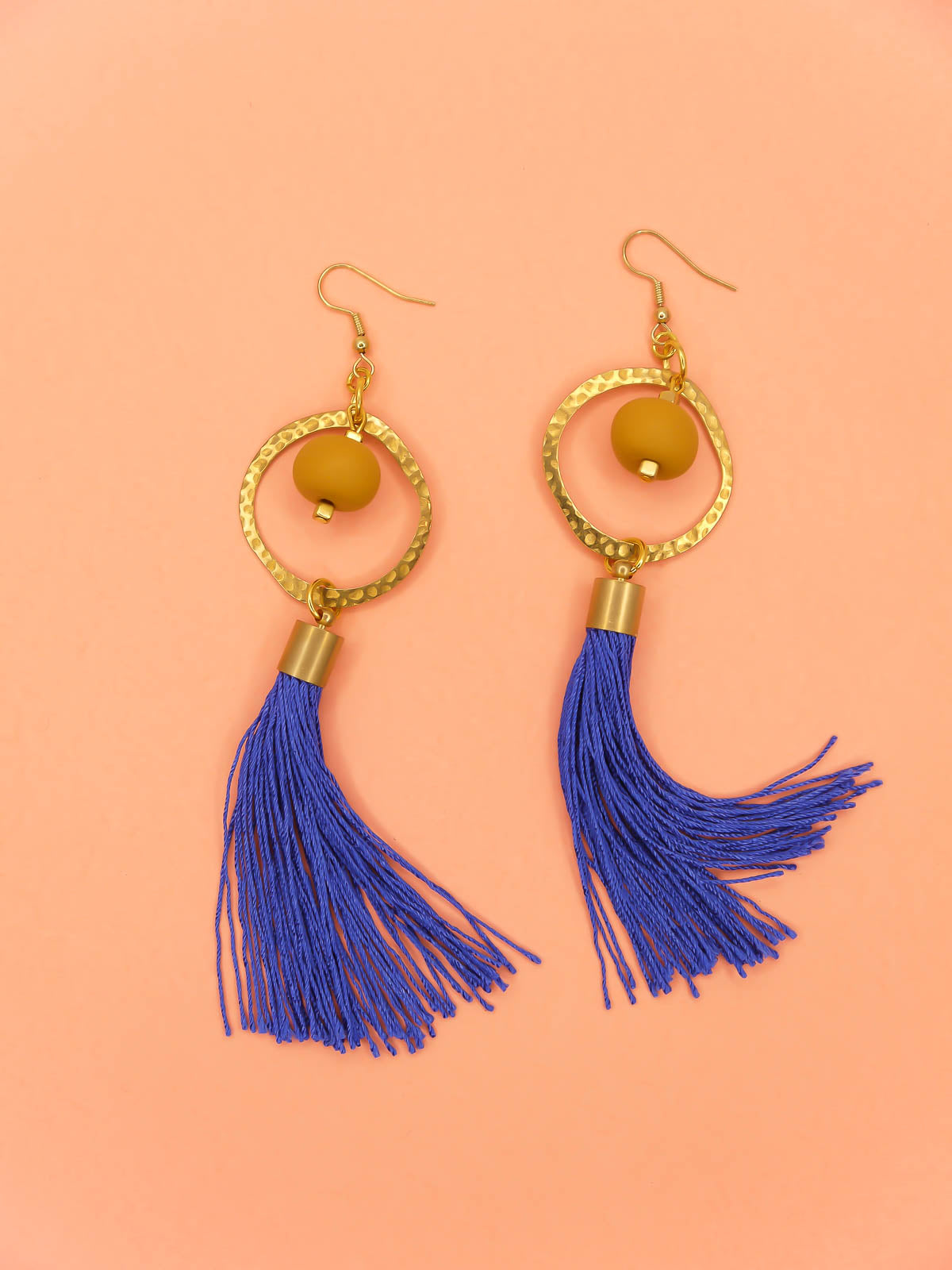 Long tassel statement earrings with gold plated ear wires, connected to a textured brass hoop with a mustard polymer clay bead dangling in the centre & a cobalt blue long tassel hung from the hoop