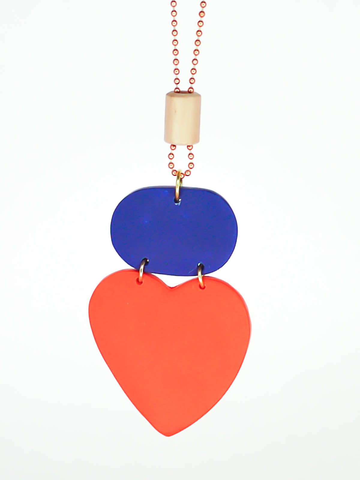 Colour block heart pendant necklace made out of lightweight polymer clay with a red heart, connected to a cobalt blue rectangle and a wooden tube bead hung on a copper ball chain