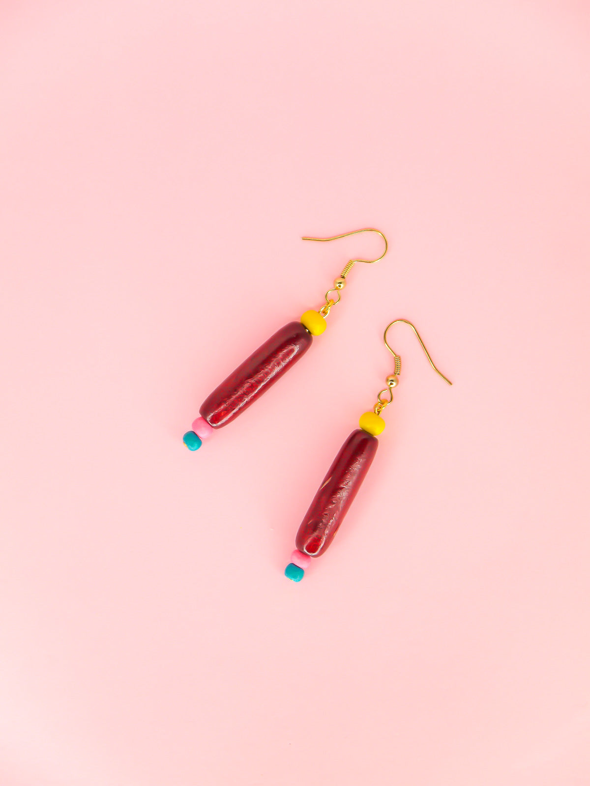 Colourful lightweight wooden bead dangle earrings of various shaped beads in yellow, mahogany, pink & blue, hung from gold plated ear wires