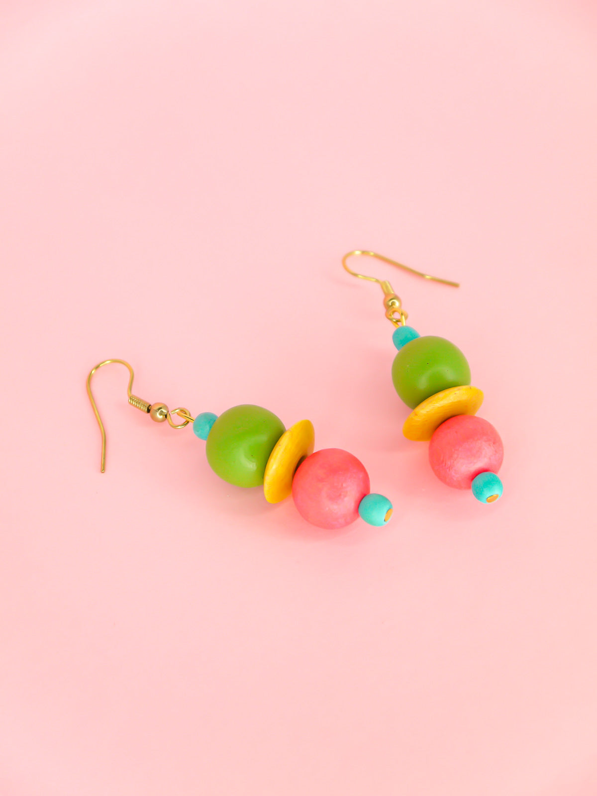 Colourful lightweight dangle earrings in wooden beads of various shapes in blue, green, yellow & pink. Hung from gold plated ear wires.