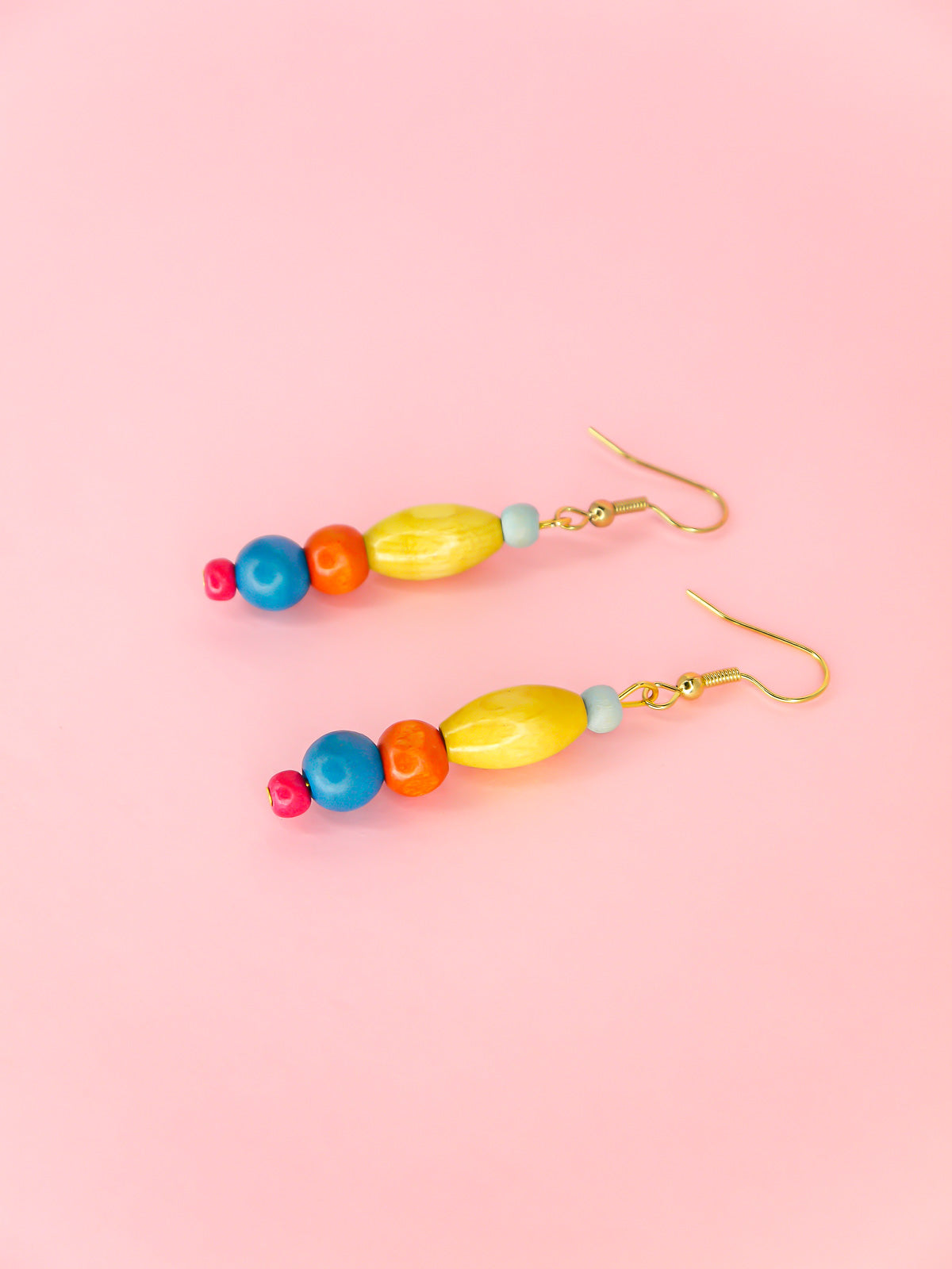 Colourful lightweight wooden bead dangle earrings in various shaped beads in blue, yellow, orange & pink, hung from gold plated ear wires