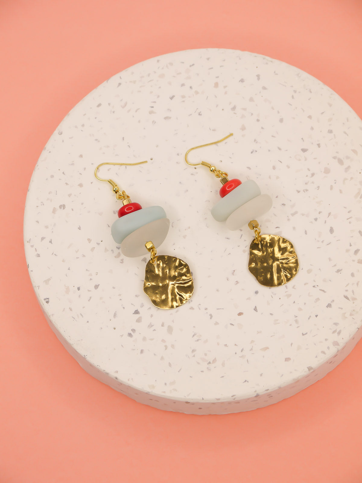 Gemstone crystal earrings with a stack of coral, amazonite and crystal quartz beads with a textured brass medallion charm, hung from gold plated ear wires