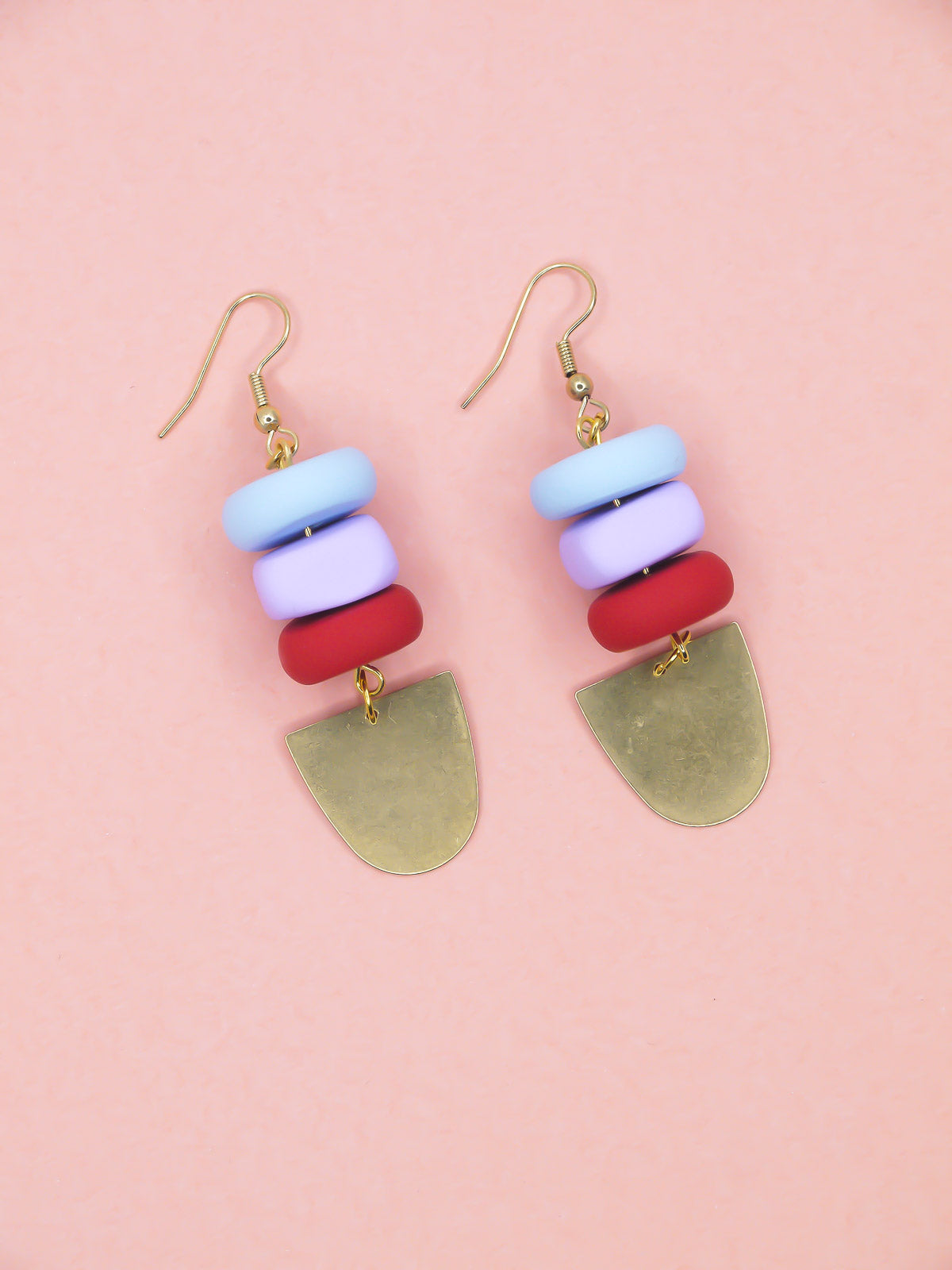 Colorful beaded earrings with gold hooks on a pink background