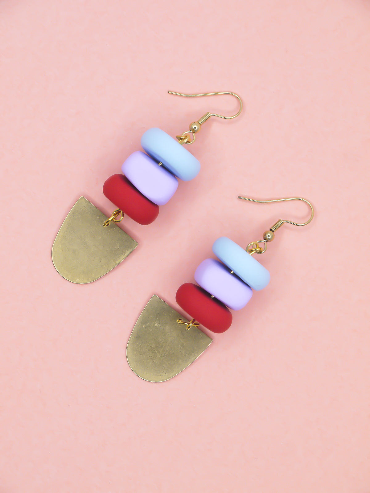 Colorful beaded earrings with gold hooks on a pink background