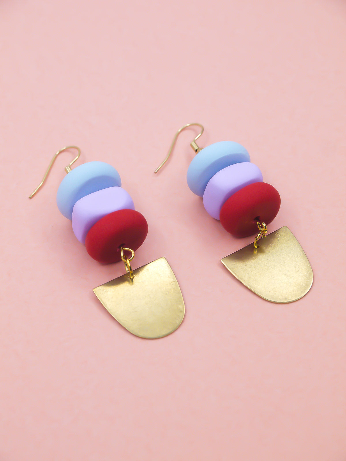 Colorful beaded earrings with gold hooks on a pink background