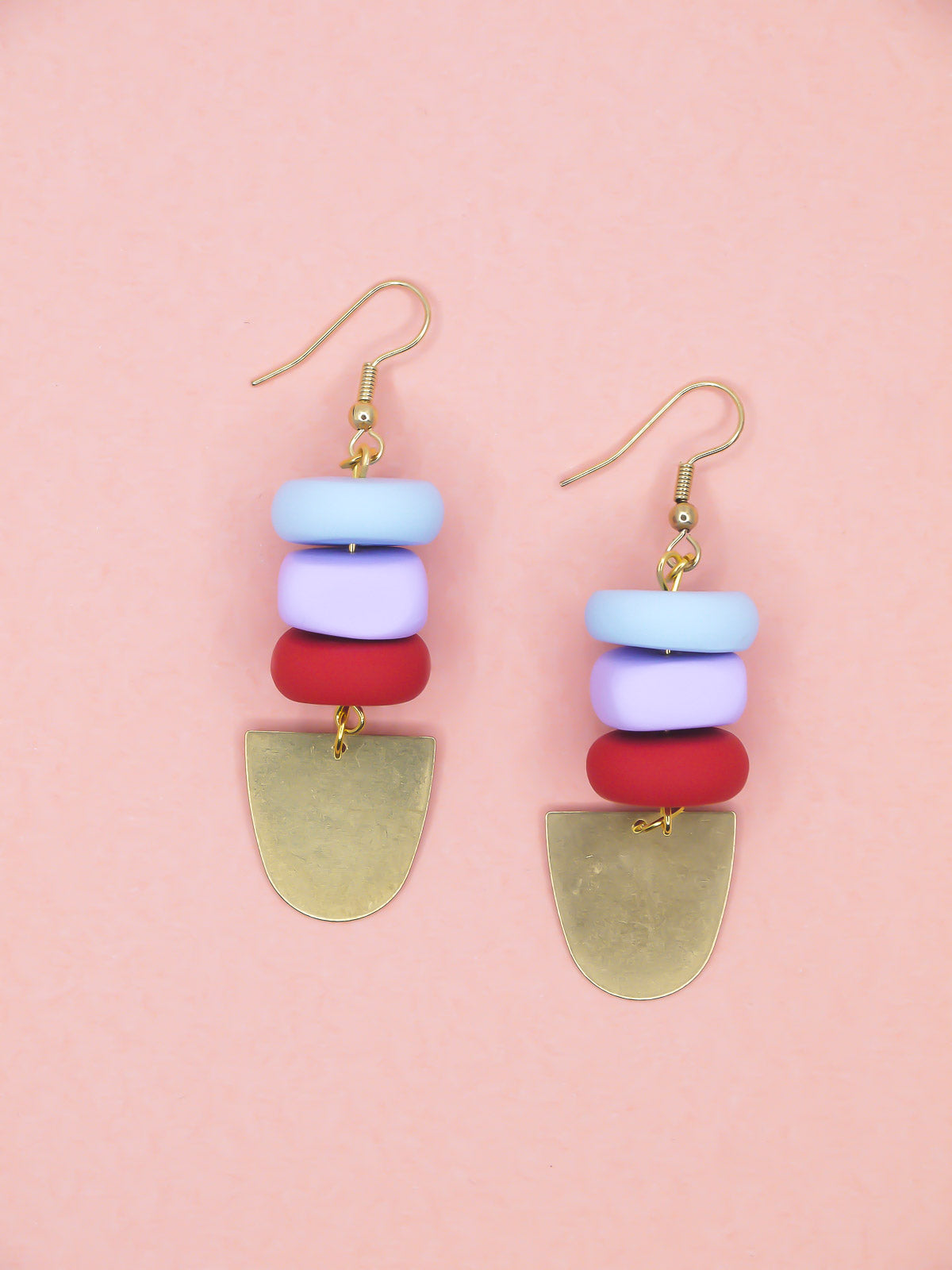 Colorful beaded earrings with gold hooks on a pink background
