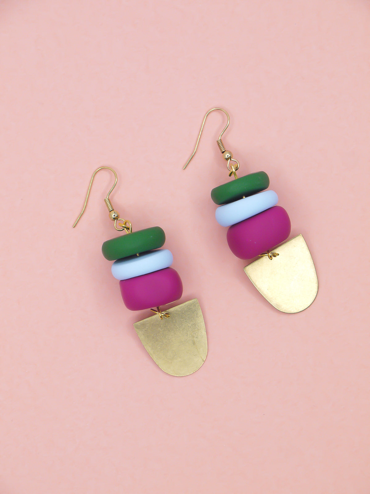 Colourful beaded earrings in green, blue & pink with gold accents on a pink background