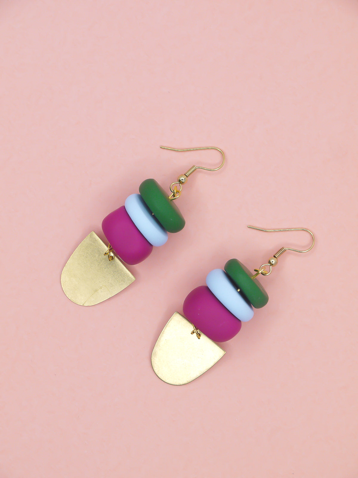 Colourful beaded earrings in green, blue & pink with gold accents on a pink background