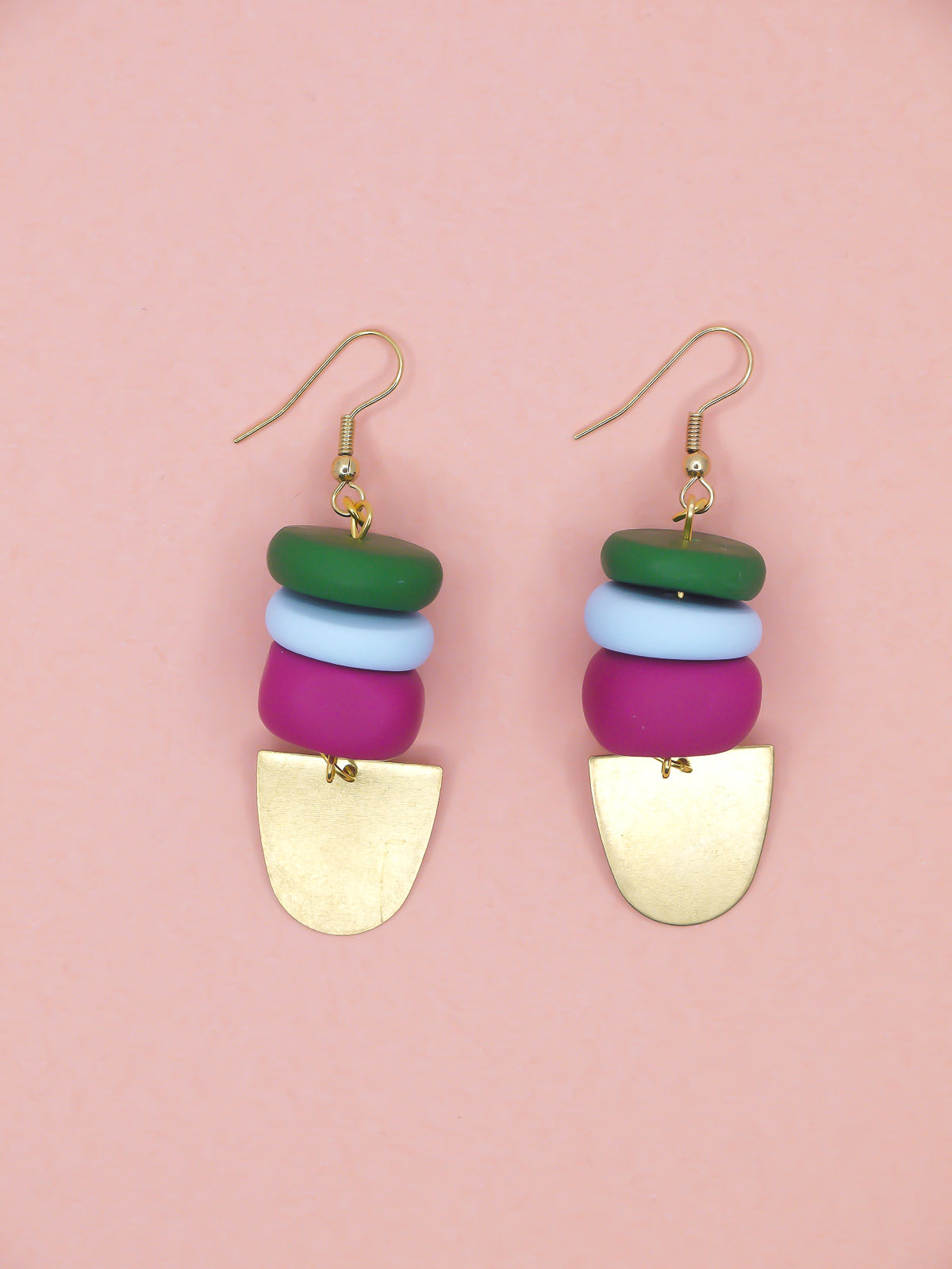 Colourful beaded earrings in green, blue & pink with gold accents on a pink background