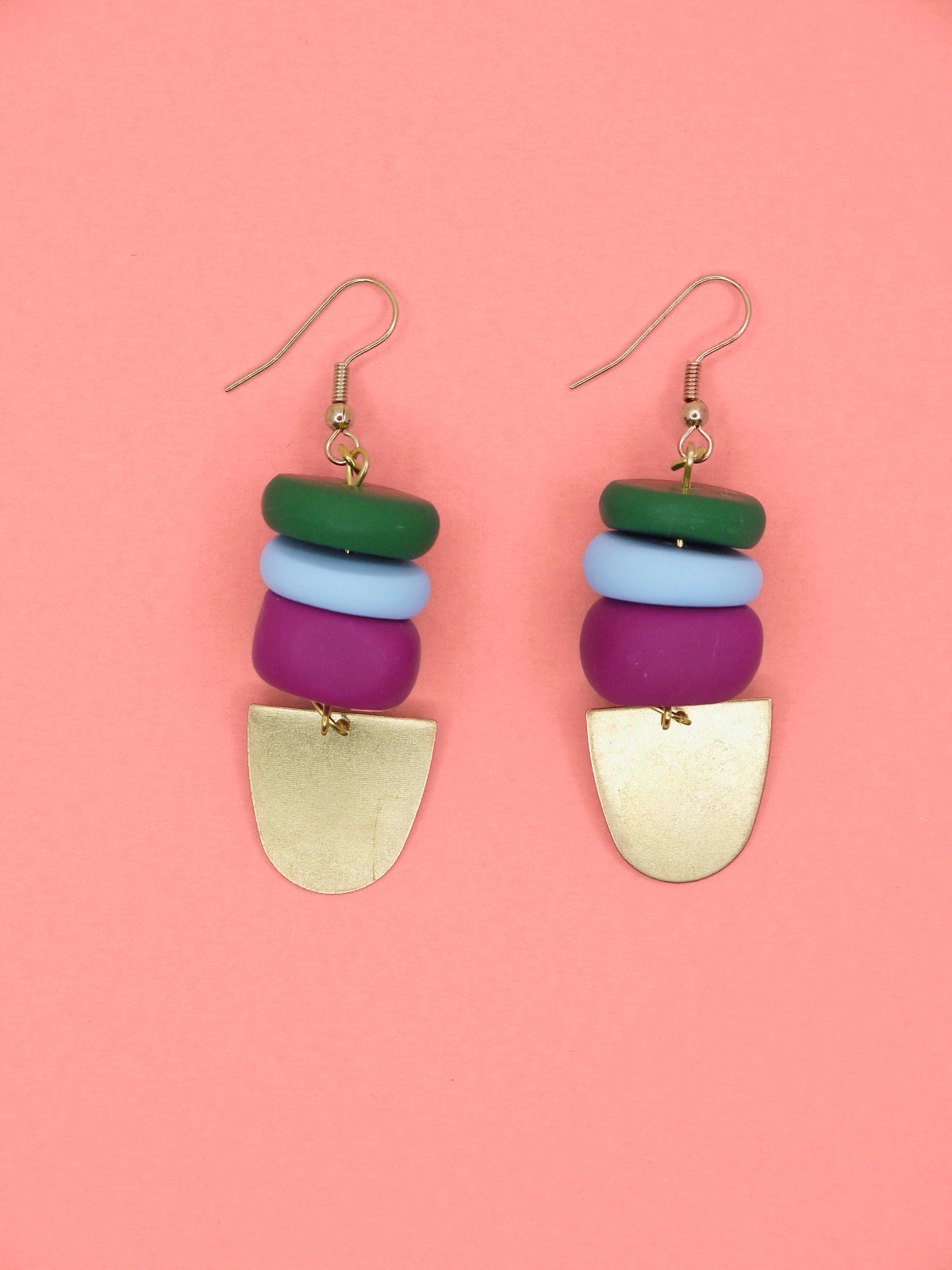 Colourful beaded earrings in green, blue & pink with gold accents on a pink background