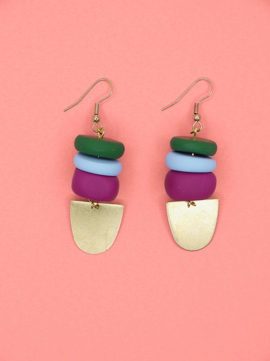Colourful beaded earrings in green, blue & pink with gold accents on a pink background