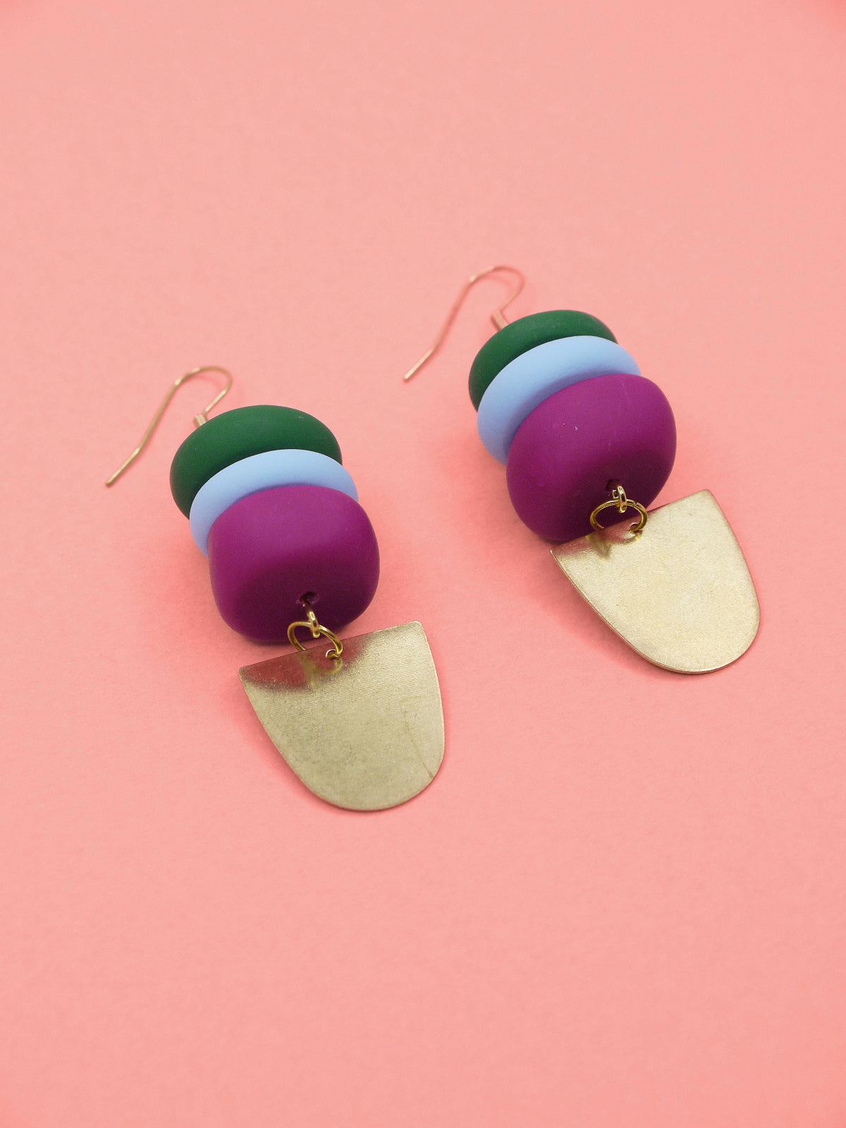 Colourful beaded earrings in green, blue & pink with gold accents on a pink background