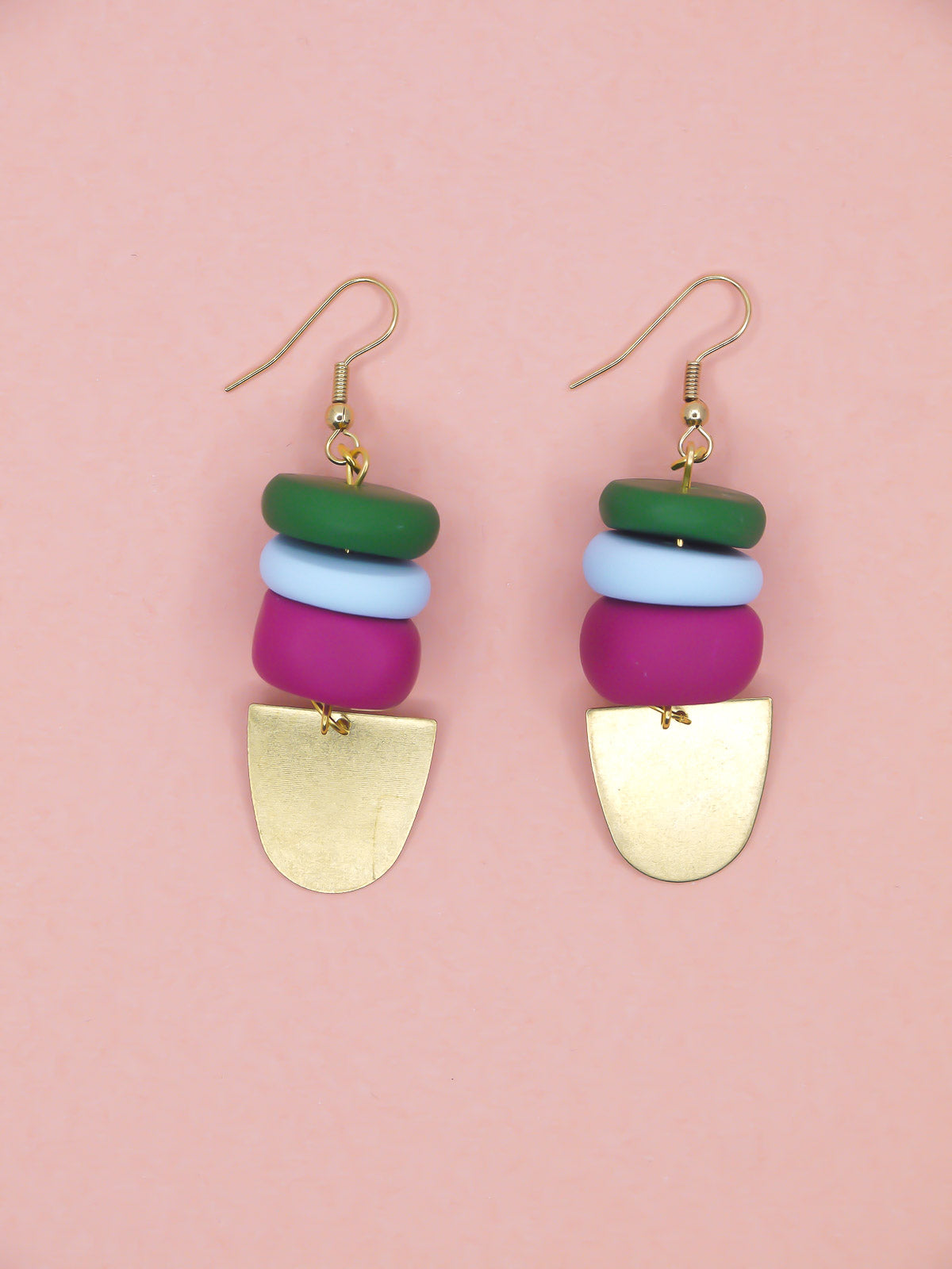 Colourful beaded earrings in green, blue & pink with gold accents on a pink background