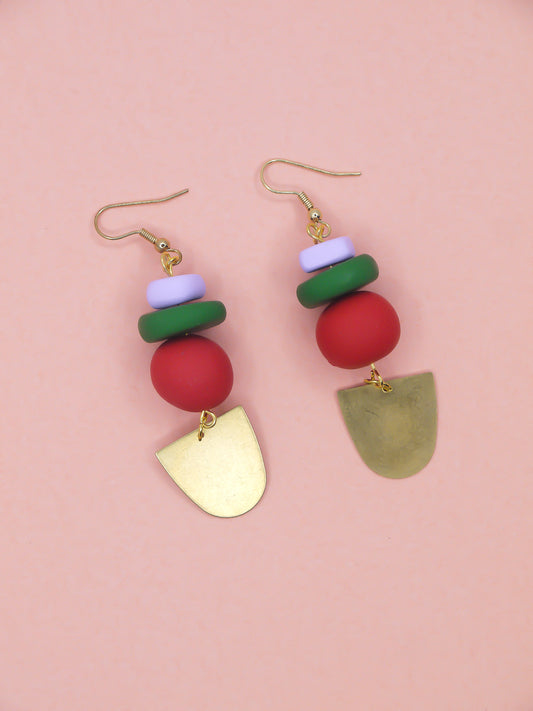 Colorful beaded earrings with gold accents on a pink background