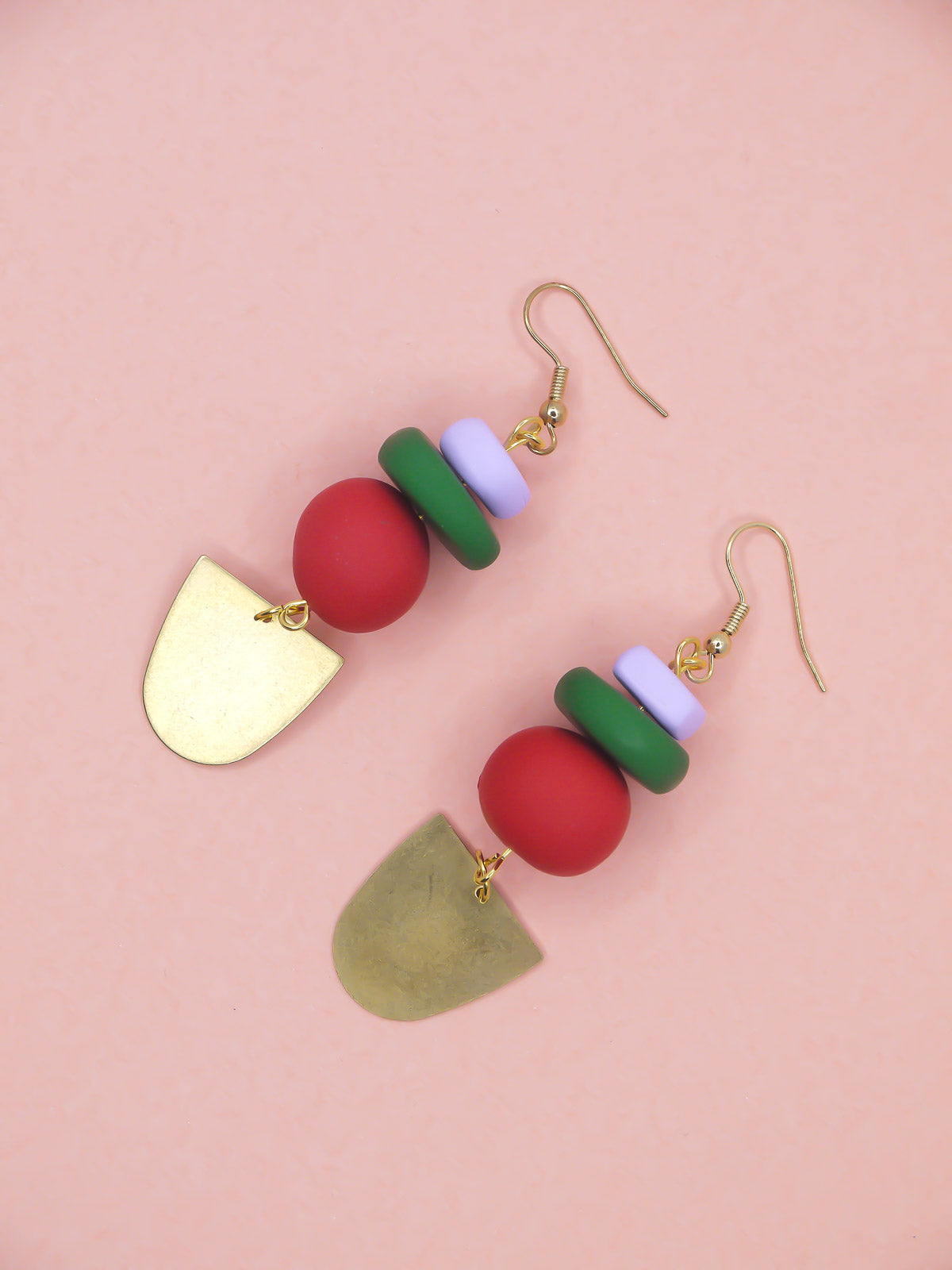 Colorful earrings with geometric shapes on a pink background