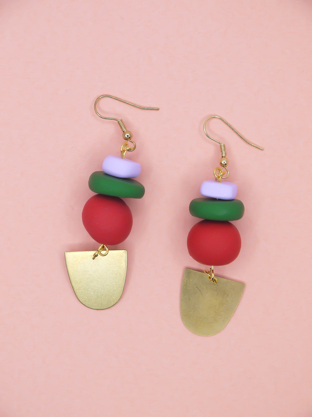 Colorful beaded earrings with gold accents on a pink background