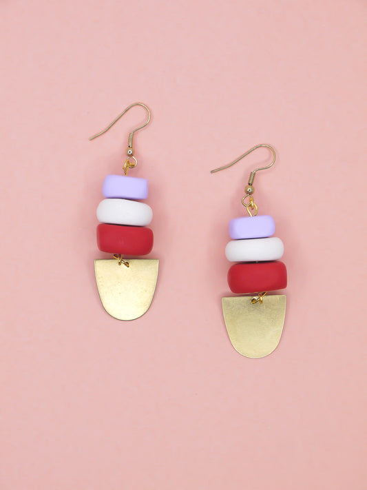 Colourful beaded earrings with gold accents on a pink background