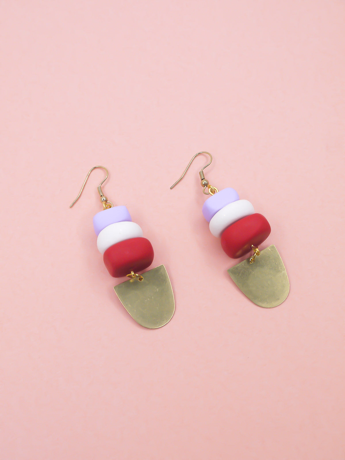 Colorful beaded earrings with a gold accent on a pink background