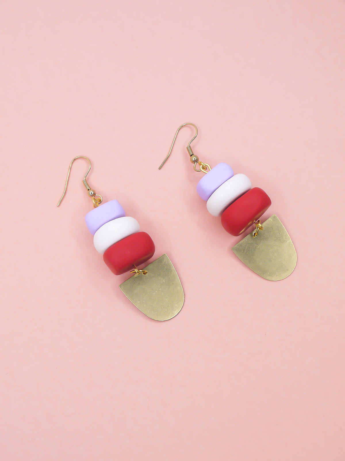 Colorful earrings with geometric shapes on a pink background