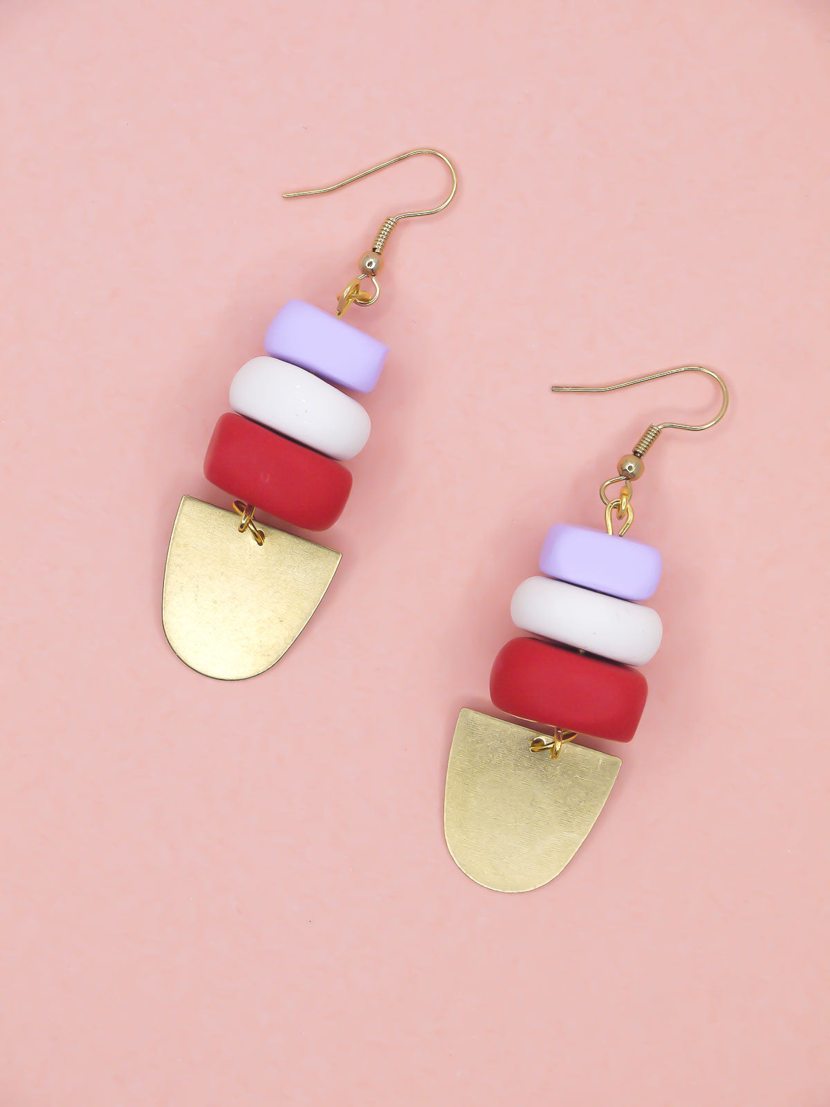 Colorful beaded earrings with gold accents on a pink background