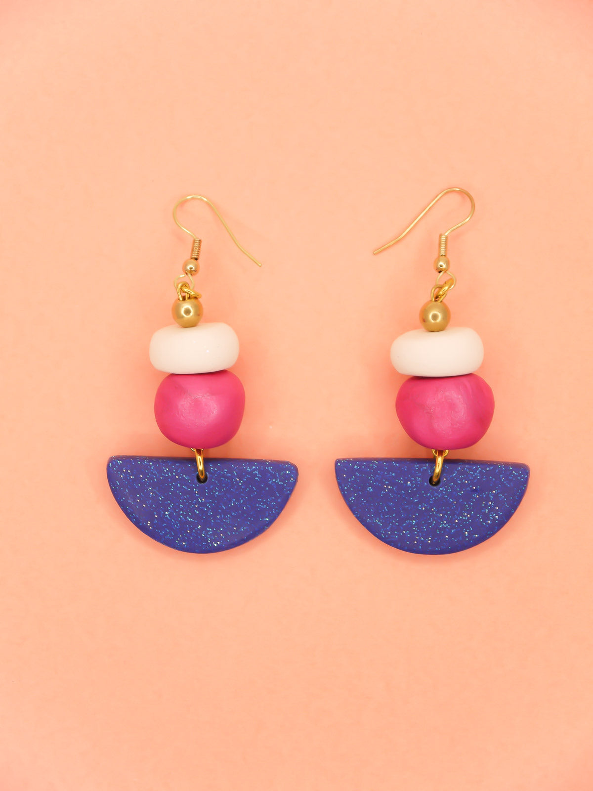 Geometric dangle statement earrings  with a blue glitter semi circle, hand rolled beads in pink metallic and white glitter with a brass ball bead hung from gold plated ear wires